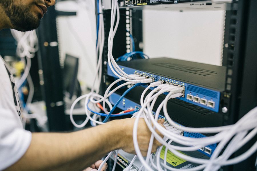 Técnico de TI configurando cabos em rack de servidor